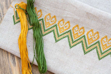 Ukrainian embroidery on the linen fabric and thread embroidery on a wooden table, selective focusの写真素材