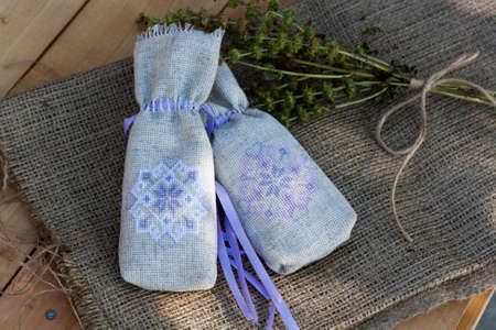 Sachet with ukrainian embroidery, sheaf of wheat and dried herbs on wooden backgroundの写真素材