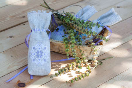 Sachet with ukrainian embroidery, sheaf of wheat and dried herbs on wooden backgroundの写真素材