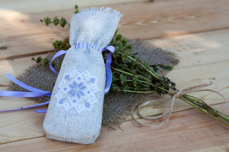 Sachet with ukrainian embroidery, sheaf of wheat and dried herbs on wooden backgroundの写真素材