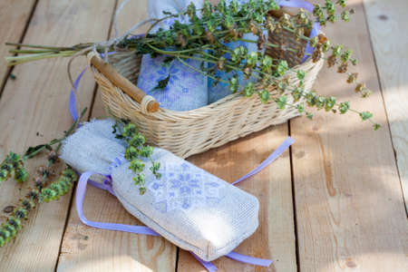 Sachet with ukrainian embroidery, sheaf of wheat and dried herbs on wooden backgroundの写真素材