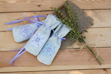 Sachet with ukrainian embroidery, sheaf of wheat and dried herbs on wooden backgroundの写真素材