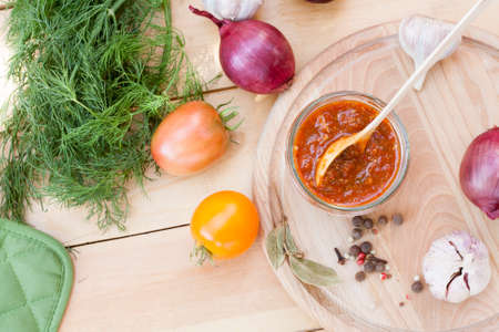 Homemade tomato sauce in glass jar with fresh tomatos, garlic, onion, herbs and spicesの写真素材