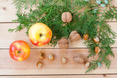 Christmas sweets, apples, nuts and green arborvitae branch on a wooden tableの写真素材