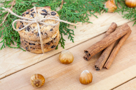 Homemade Christmas cookies with chocolate, nuts, cones, cinnamon and green arborvitae branch on a wooden tableの写真素材