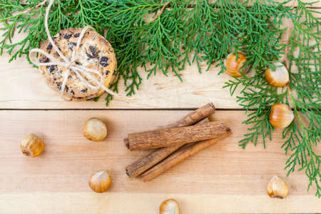 Homemade Christmas cookies with chocolate, nuts, cones, cinnamon and green arborvitae branch on a wooden tableの写真素材