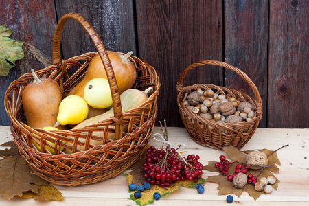 Autumn still life with pumpkins in basket and autumn berry on old wooden background, closeup