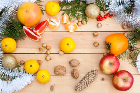Tangerines in Christmas decor with Christmas tree, nuts and apples on light wooden backgroundの写真素材