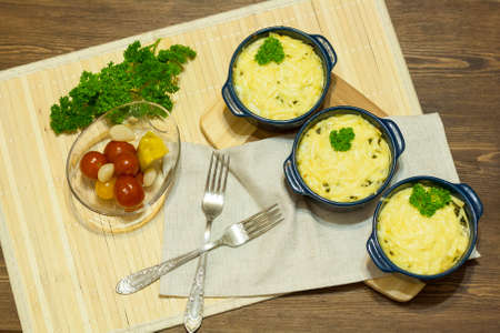 Julienne with mushrooms and cream. Mushroom and cheese gratin in ceramic bowls, on wooden backgroundの写真素材