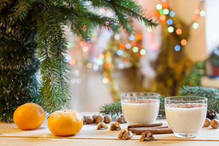 Vanilla panna cotta with chocolate, tangerines, cones, cinnamon and nuts in Christmas decor with Christmas tree on colorful background bokehの写真素材