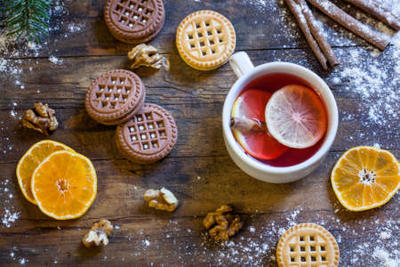 Tea, tangerines and cookies in Christmas decor with Christmas tree, nuts and apples on dark wooden backgroundの写真素材