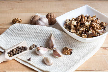 Walnuts in a old white bowl, garlic and pepper on a wooden backgroundの写真素材