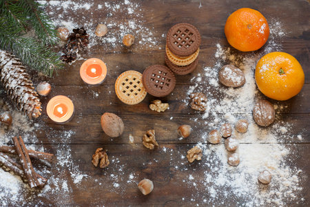Tangerines and cookies in Christmas decor with Christmas tree, nuts and apples on dark wooden backgroundの写真素材