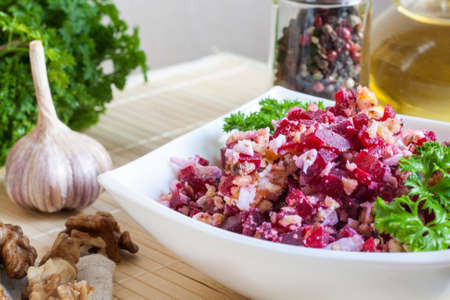 Beetroot salad with walnuts and cream sauce. Nuts, garlic, salt, pepper, herbs, boiled eggs and oil on a wooden table.の写真素材