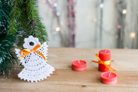 Christmas angel in tree and red candles on colorful background bokeh among Christmas and New Year decorの写真素材