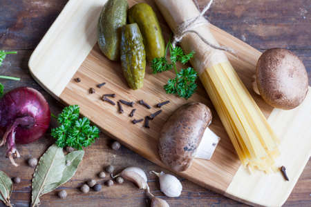 Long Noodles Linguine, pickled cucumbers gherkins, Champignon mushrooms, herbs, spices and vegetables on wooden tableの写真素材