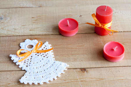 Christmas angel and red candles on light wooden backgroundの写真素材
