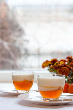 Vanilla and orange Panna Cotta in the cup on white saucerの写真素材