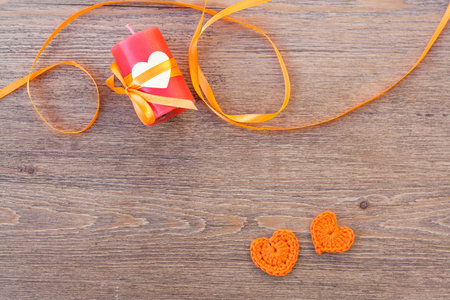 Valentines day crochet orange hearts, ribbon and candle on wooden table.の写真素材