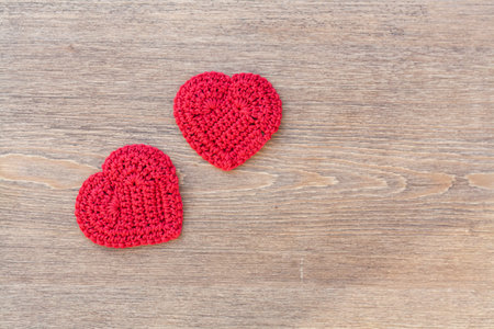 Two red crochet hearts on wooden background for Valentines day