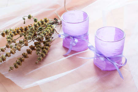 Two aromatic candles in glass candlesticks with lavender paper on table close upの写真素材