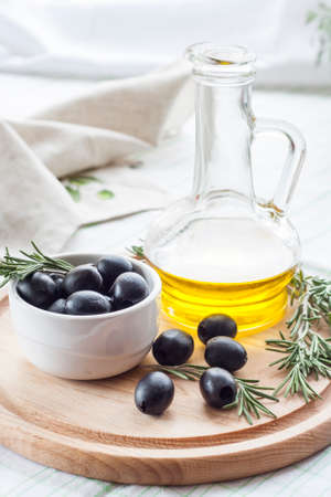 Bottle of olive oil and marinated black olives. Marinated black olives in ceramic bowl and wooden spoon with bottle of olive oil.の写真素材