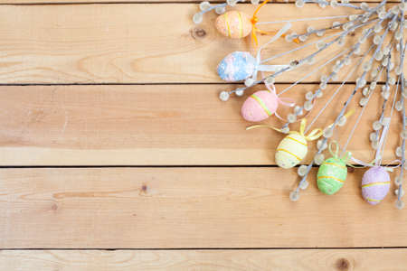 Pussy willow and handmade Happy Easter eggs on a light wooden backgroundの写真素材