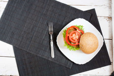 Homemade hamburger on white plate, black makisu on white wooden tableの写真素材