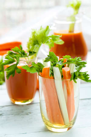 Fresh carrots and celery in glass with fresh carrot juice and parsley on black backgroundの写真素材