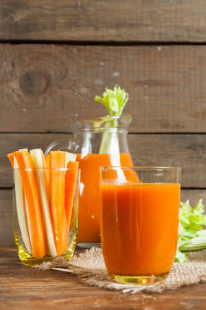Fresh carrot juice with carrots and celery on dark wooden backgroundの写真素材