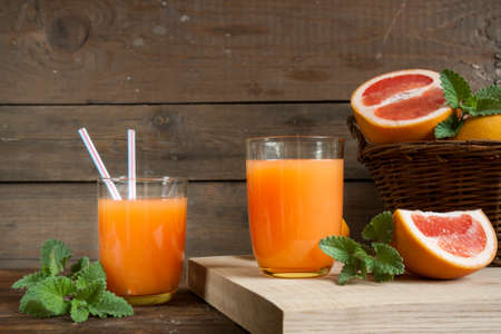 Natural and fresh grapefruit juice in glass with freshly harvested grapefruit in basket on dark wooden backgroundの写真素材