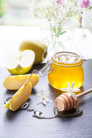 Apple and honey, traditional food of jewish New Year - Rosh Hashana, with flowers on black boardの写真素材