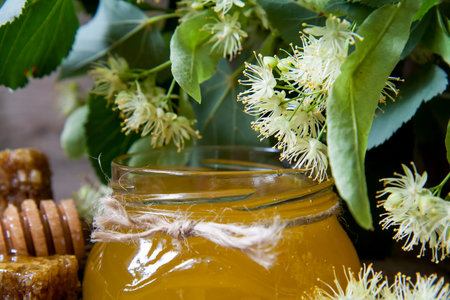 Jar with honey, honeycomb with pollen and linden flowers on a dark wooden backgroundの写真素材