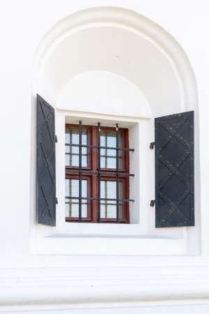 Wooden window with metal hinged shutters decorated with forged grillの写真素材