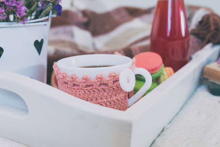 Breakfast in bed with hot coffee and macaroons. Healthy breakfast kept on bed with books and flowers Close up of a cup of coffee with cookies, fresh juice and grapefruit on wooden tray in bed. Tonedの写真素材