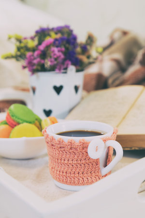 Breakfast in bed with hot coffee and macaroons. Healthy breakfast kept on bed with books and flowers...