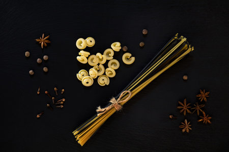 Traditional and black uncooked Italian pasta Linguine, Italian pasta Cappelletti with  spices on black stone background.の写真素材