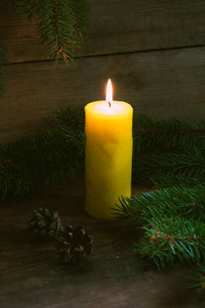 Christmas lighted candle with christmas tree and cones on wooden backgroundの写真素材
