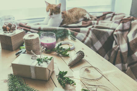 Wrapping eco Christmas packages with brown paper, string and natural branches and decor elements on wooden tableの写真素材