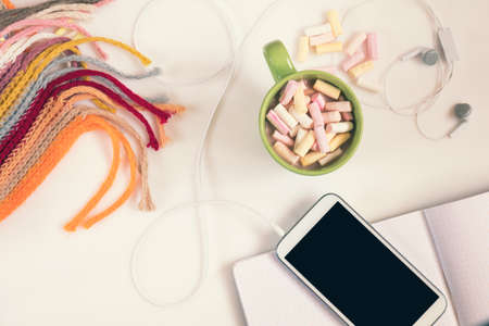  Office desk with cup of hot chocolate, phone, notebook  and checkered scarf. Flat lay white background. Coloring and processing photo.の写真素材