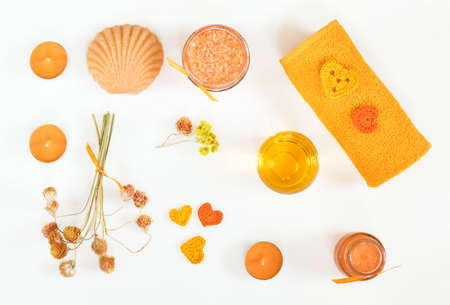 Spa attributes sets. Honey bath salts, dry flowers, soap, cosmetic cream, cosmetic oil, candles, shell, stone and towel. Yellow orange concept. Flat lay on white background top view.の写真素材