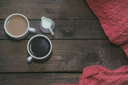Cup of black coffee, cup of coffee with milk, cream. Pink woven scarf. Dark wooden background. Beautiful vintage coffee groundwork. Coloring and processing photo.の写真素材