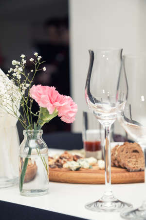 Close up picture of wine glasses with flower and empty glasses in restaurant. Serving table prepared for event party or wedding. Soft focus, selective focus. Toned.の写真素材