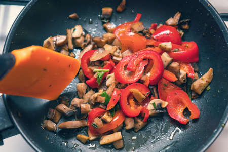 Mushrooms and fresh sweet red pepper in the pan for cooking. Spices and fresh parsley. Shallow depth of field. Tonedの写真素材