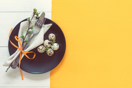 Easter table setting with spring flowers and cutlery. Rustic orange table cloth on white wood...