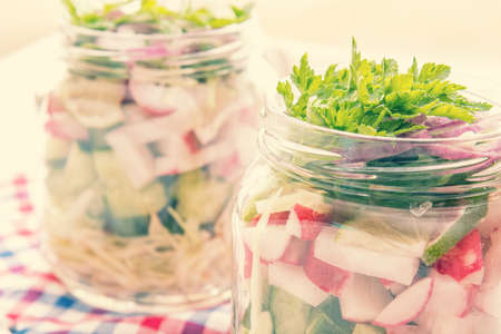 Homemade healthy salads with vegetables, onion, parsley and lettuce in jar. Toning. Selective focus.の写真素材