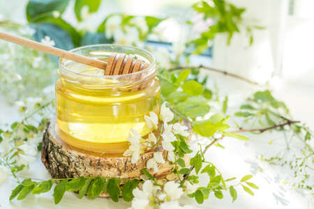 Honey in glass jars with acacia blossoms on windowsill. Shallow depth of field.の写真素材