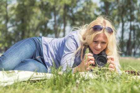 Professional woman photographer taking outdoor with prime lens, during a sunny day in the spring park. Shallow depth of field. Toned.の写真素材