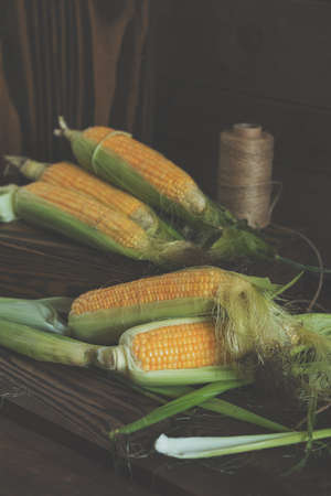 Fresh sweet corn on cobs on rustic wooden table, close up. Toned. Shallow depth of field.の写真素材