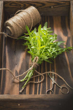 Fresh green arugula bouquet and supplies in wooden box. Top viewの写真素材